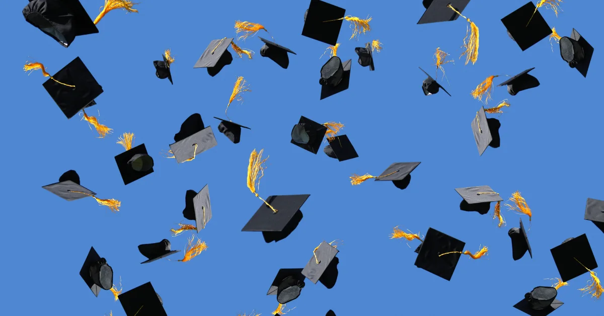 Graduation caps thrown against a blue sky